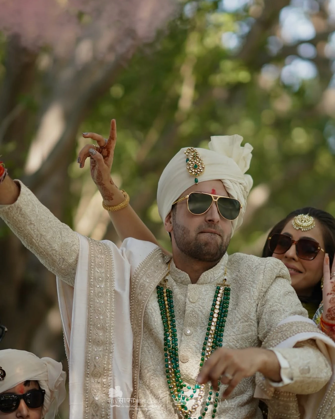 Groom in an ivory wedding safa with emerald jewellery for Destination Wedding Safa